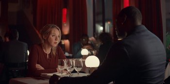 Movie still from “Lupin” (2021), created by Tigran Rosine – A woman sitting at a table in front of a man with wine glasses; Medium shot, Over the shoulder angle