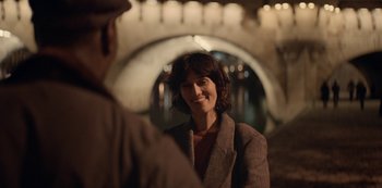 Movie still from “Lupin” (2021), created by Tigran Rosine – A woman in a brown jacket smiling at a man in a brown suit; Close Up shot, Over the shoulder angle