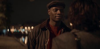 Movie still from “Lupin” (2021), created by Tigran Rosine – A man wearing a hat and a brown jacket; Close Up shot, Over the shoulder angle