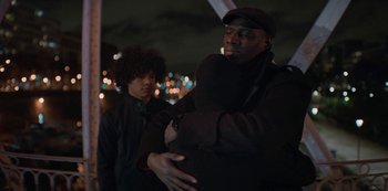 Movie still from “Lupin” (2021), created by Tigran Rosine – A man standing next to another man on a bridge; Medium shot, Over the shoulder angle