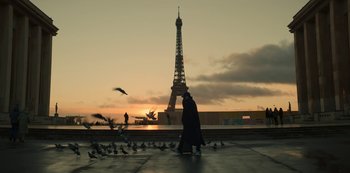 Movie still from “Lupin” (2021), created by Tigran Rosine – A person standing in front of the eiffel tower at sunset; Extreme Wide shot, Low angle
