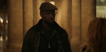Movie still from “Lupin” (2021), created by Tigran Rosine – A man wearing a brown hat and a jacket; Medium shot, Over the shoulder angle