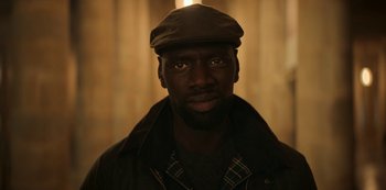 Movie still from “Lupin” (2021), created by Tigran Rosine – A person wearing a hat; Close Up shot, Over the shoulder angle
