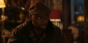 Movie still from “Lupin” (2021), created by Tigran Rosine – A man wearing a brown hat and a jacket; Close Up shot, Over the shoulder angle