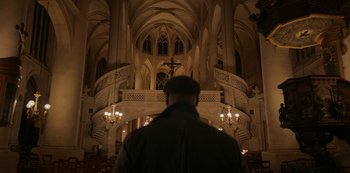Movie still from “Lupin” (2021), created by Tigran Rosine – A man standing in front of an ornate cathedral; Extreme Wide shot, Low angle