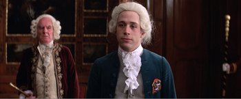 Movie still from “Amadeus” (1984), directed by Milos Forman – A man in a wig and a blue jacket; Medium shot, Over the shoulder angle