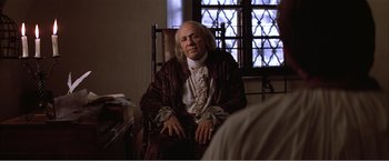 Movie still from “Amadeus” (1984), directed by Milos Forman – A man sitting in a chair in front of a window; Medium shot, Over the shoulder angle