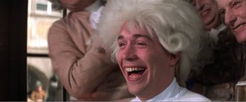 Movie still from “Amadeus” (1984), directed by Milos Forman – A man in a white wig and a white shirt laughing; Close Up shot, Low angle
