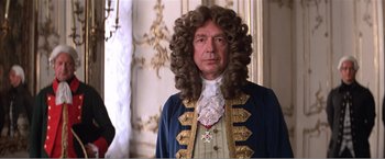 Movie still from “Amadeus” (1984), directed by Milos Forman – A man in a wig and a blue jacket; Medium shot, Over the shoulder angle
