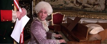 Movie still from “Amadeus” (1984), directed by Milos Forman – A man wearing a wig sitting at a piano; Medium shot, High angle
