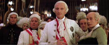 Movie still from “Amadeus” (1984), directed by Milos Forman – A man in a white suit and a red tie; Medium shot, Low angle