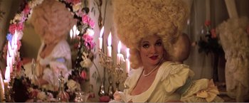 Movie still from “Amadeus” (1984), directed by Milos Forman – A woman with a large blonde wig on her head; Close Up shot, Over the shoulder angle