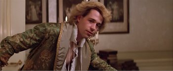 Movie still from “Amadeus” (1984), directed by Milos Forman – A man in a green and gold jacket sitting in a room; Close Up shot, Over the shoulder angle