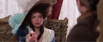 Movie still from “Amadeus” (1984), directed by Milos Forman – A woman with a hat on holding a piece of cake; Close Up shot, Over the shoulder angle
