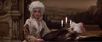 Movie still from “Amadeus” (1984), directed by Milos Forman – A woman dressed as marie antoinette in a room with lit candles; Medium shot, Over the shoulder angle