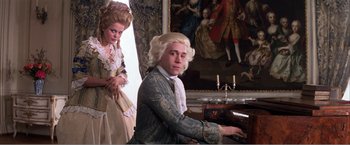Movie still from “Amadeus” (1984), directed by Milos Forman – A man and a woman dressed in period clothing playing the piano; Medium shot, Low angle