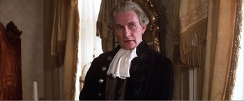 Movie still from “Amadeus” (1984), directed by Milos Forman – An older man wearing a wig and a wig stand in front of a window; Close Up shot, Low angle