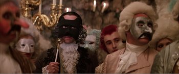 Movie still from “Amadeus” (1984), directed by Milos Forman – A group of people wearing masks in a room; Medium shot, Over the shoulder angle