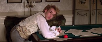 Movie still from “Amadeus” (1984), directed by Milos Forman – A man in a white shirt is writing on a table; Medium shot, Over the shoulder angle