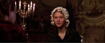Movie still from “Amadeus” (1984), directed by Milos Forman – A woman wearing a white hat and a black shirt in front of candles; Close Up shot, Over the shoulder angle