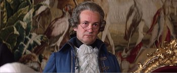 Movie still from “Amadeus” (1984), directed by Milos Forman – A man in a wig and glasses is posing for a picture; Close Up shot, Low angle