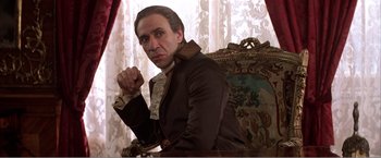 Movie still from “Amadeus” (1984), directed by Milos Forman – A man sitting in a chair wearing a brown jacket; Medium shot, Low angle