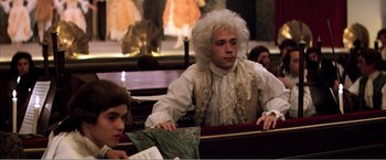 Movie still from “Amadeus” (1984), directed by Milos Forman – A man sitting in front of another man in front of a mirror; Medium shot, Over the shoulder angle