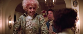 Movie still from “Amadeus” (1984), directed by Milos Forman – A man in a pink wig and a man in a pink wig; Medium shot, Over the shoulder angle