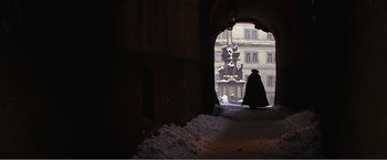 Movie still from “Amadeus” (1984), directed by Milos Forman – A man in a black cape standing under a bridge; Wide shot, Over the shoulder angle