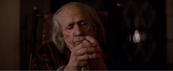 Movie still from “Amadeus” (1984), directed by Milos Forman – An old man sitting in a chair with his hands clasped together; Close Up shot, High angle