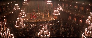 Movie still from “Amadeus” (1984), directed by Milos Forman – A large crowd of people sitting in a room with lit candles; Extreme Wide shot, High angle