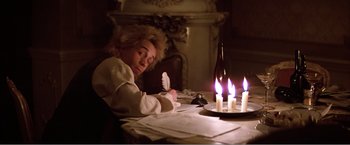 Movie still from “Amadeus” (1984), directed by Milos Forman – A woman sitting at a table with a lit candle in front of a wine bottle; Medium shot, High angle