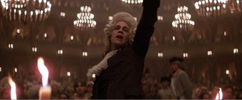 Movie still from “Amadeus” (1984), directed by Milos Forman – A man in a wig raising his arm in the air; Medium shot, Low angle