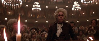 Movie still from “Amadeus” (1984), directed by Milos Forman – A man in a wig standing in front of an audience; Medium shot, Low angle
