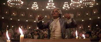 Movie still from “Amadeus” (1984), directed by Milos Forman – A man in a wig and wig stands in front of an audience; Medium shot, Low angle