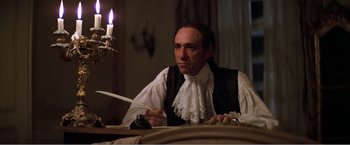 Movie still from “Amadeus” (1984), directed by Milos Forman – A man sitting at a table with a knife in his hand; Medium shot, Low angle