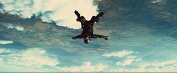 Movie still from “Kingsman: The Secret Service” (2014), directed by Matthew Vaughn – A man in a black suit parachuting into the sky; Wide shot, Low angle