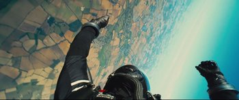 Movie still from “Kingsman: The Secret Service” (2014), directed by Matthew Vaughn – A skydiver is flying through the air over a field; Wide shot, Overhead angle