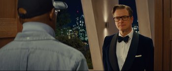 Movie still from “Kingsman: The Secret Service” (2014), directed by Matthew Vaughn – A man in a suit and tie standing next to another man in a tuxedo; Medium shot, Over the shoulder angle