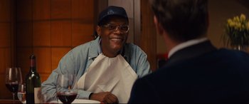 Movie still from “Kingsman: The Secret Service” (2014), directed by Matthew Vaughn – A man wearing a blue hat and a blue shirt is talking to another man in a suit; Close Up shot, Over the shoulder angle