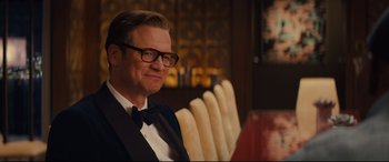 Movie still from “Kingsman: The Secret Service” (2014), directed by Matthew Vaughn – A man sitting in a chair wearing a bow tie; Medium shot, Over the shoulder angle