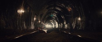 Movie still from “Kingsman: The Secret Service” (2014), directed by Matthew Vaughn – Two people are laying on the ground in a tunnel; Extreme Wide shot, High angle