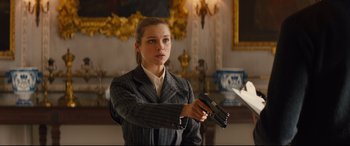 Movie still from “Kingsman: The Secret Service” (2014), directed by Matthew Vaughn – A woman holding a gun in a room; Medium shot, Low angle