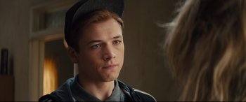 Movie still from “Kingsman: The Secret Service” (2014), directed by Matthew Vaughn – A young man with a baseball cap looking at the camera; Close Up shot, Over the shoulder angle