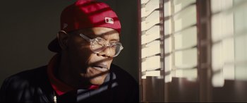 Movie still from “Kingsman: The Secret Service” (2014), directed by Matthew Vaughn – An older man wearing glasses and a red hat; Close Up shot, Low angle