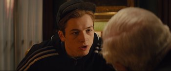 Movie still from “Kingsman: The Secret Service” (2014), directed by Matthew Vaughn – A young man wearing a hat talking to an older man; Close Up shot, Over the shoulder angle