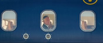 Movie still from “Kingsman: The Secret Service” (2014), directed by Matthew Vaughn – A man in a suit looking out of a porthole window; Medium shot, Low angle