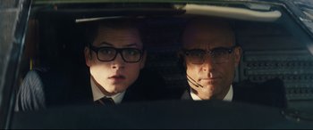 Movie still from “Kingsman: The Secret Service” (2014), directed by Matthew Vaughn – A man and a woman in a car looking out the window; Close Up shot, Low angle