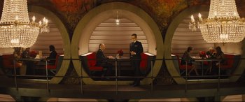 Movie still from “Kingsman: The Secret Service” (2014), directed by Matthew Vaughn – Two men in suits sitting at a table in front of each other; Wide shot, High angle