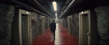 Movie still from “Kingsman: The Secret Service” (2014), directed by Matthew Vaughn – A man in a suit running down a red hallway; Extreme Wide shot, High angle